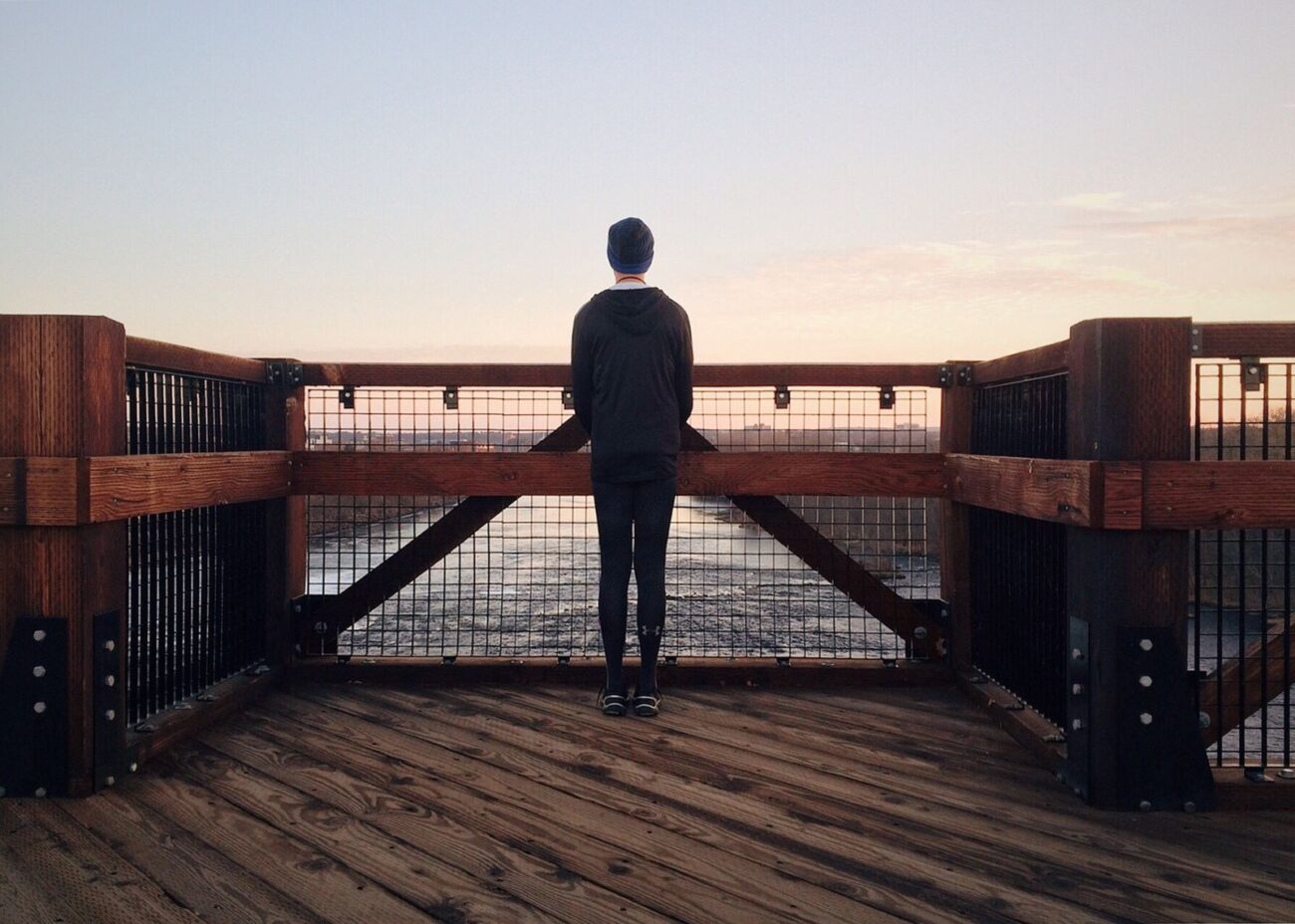A person standing alone and steady, looking out over calm water