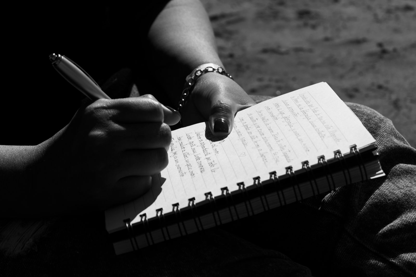 A close view of hands writing notes in a small notebook
