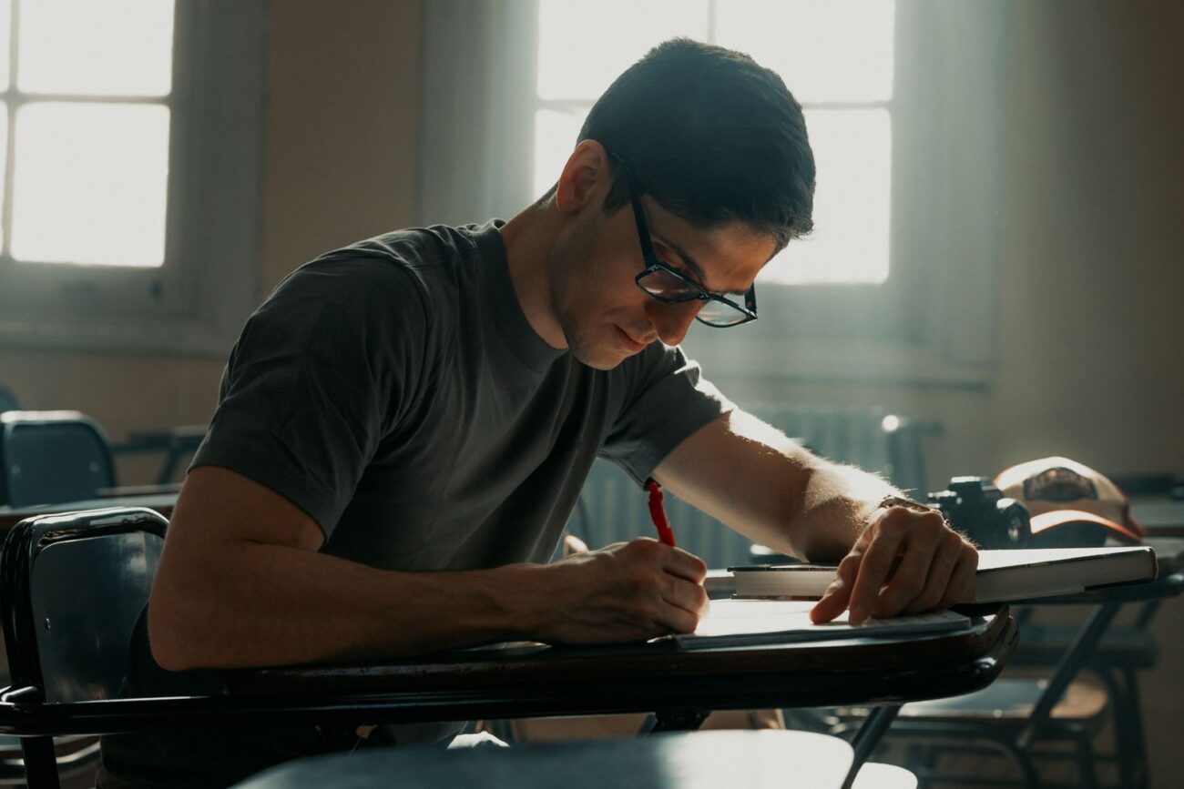 A student writing and studying at a desk in natural light