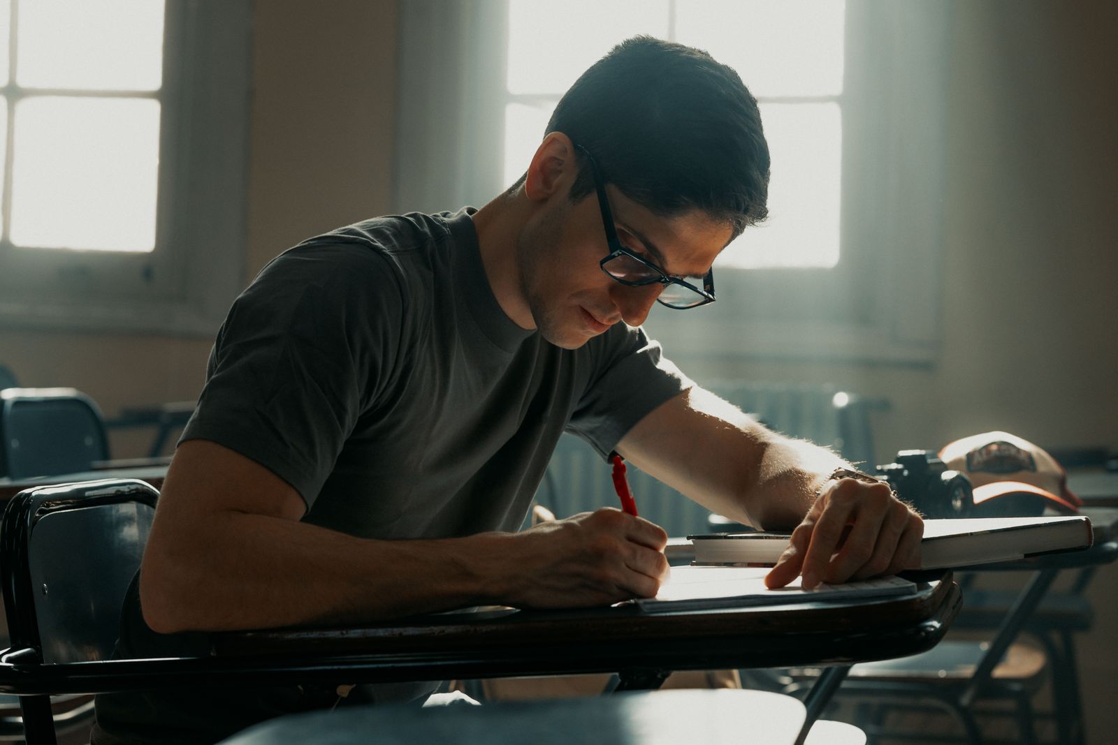 A student writing and studying at a desk in natural light