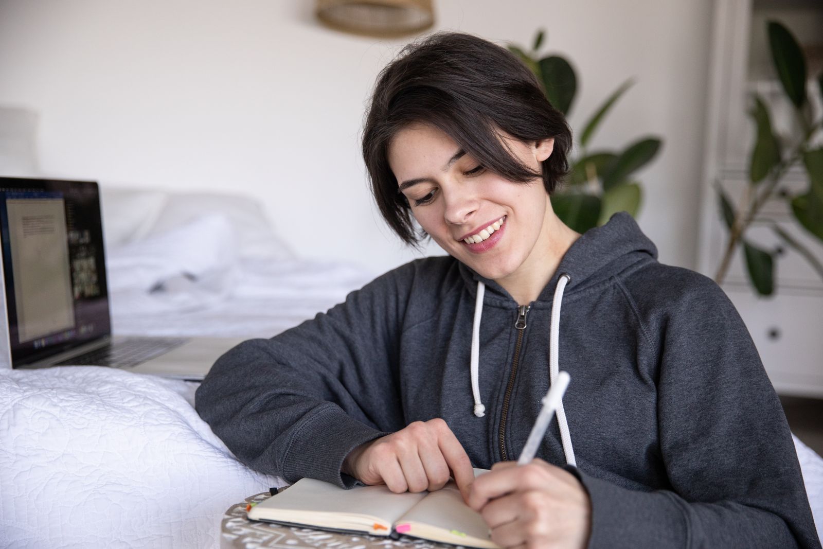 A person smiling while writing in a notebook, relaxed and engaged