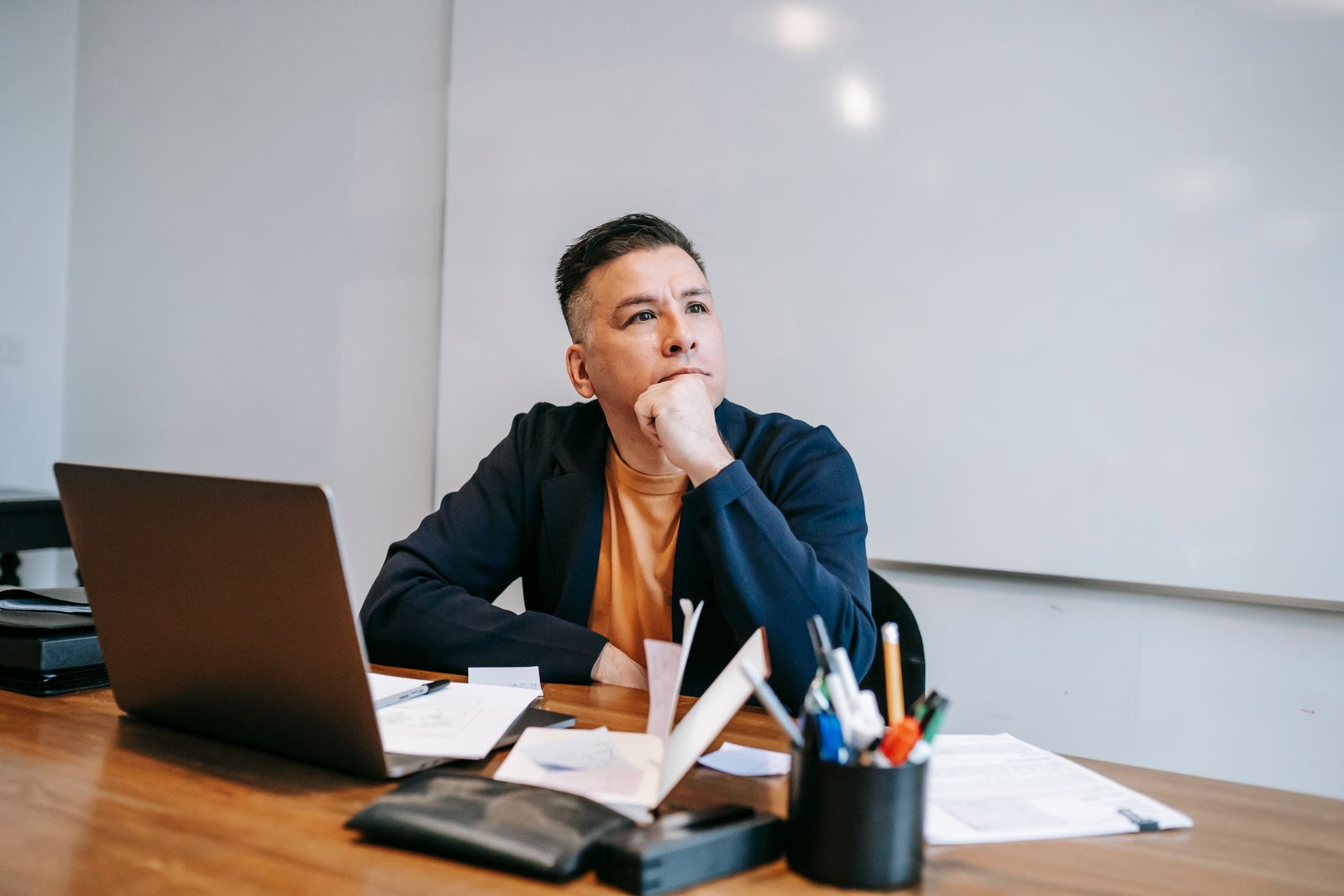 A person sitting at a desk looking stuck, staring away from their laptop
