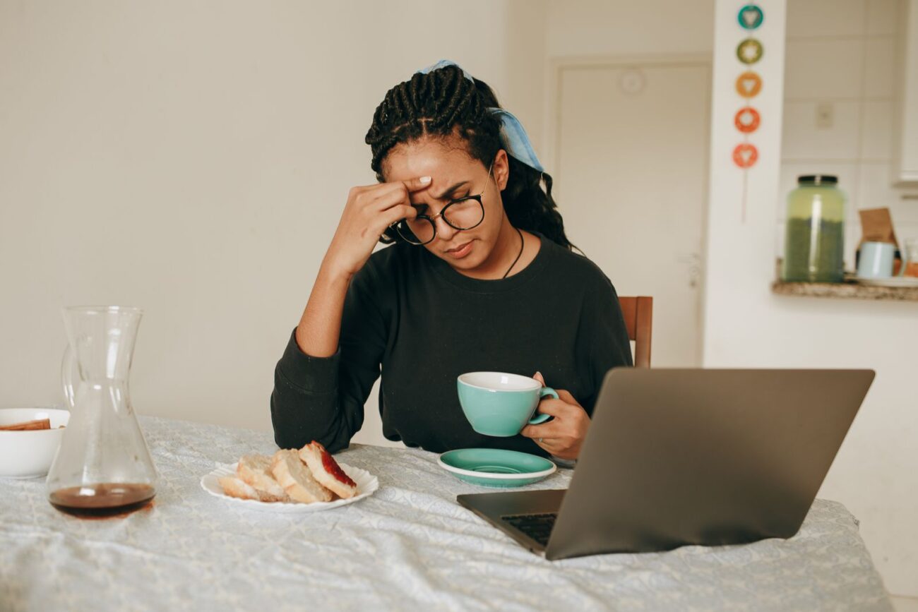 A person looking stressed and weary at a laptop in the morning
