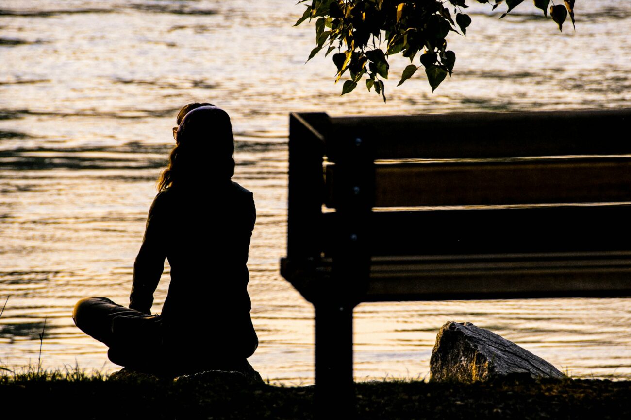A person sitting alone by the water at dusk in quiet solitude