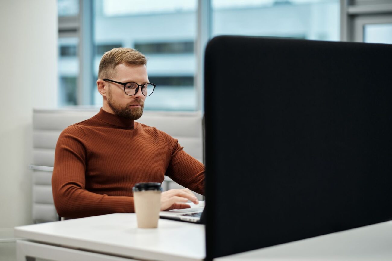 An adult working alone at a desk on a laptop, focused with no one supervising