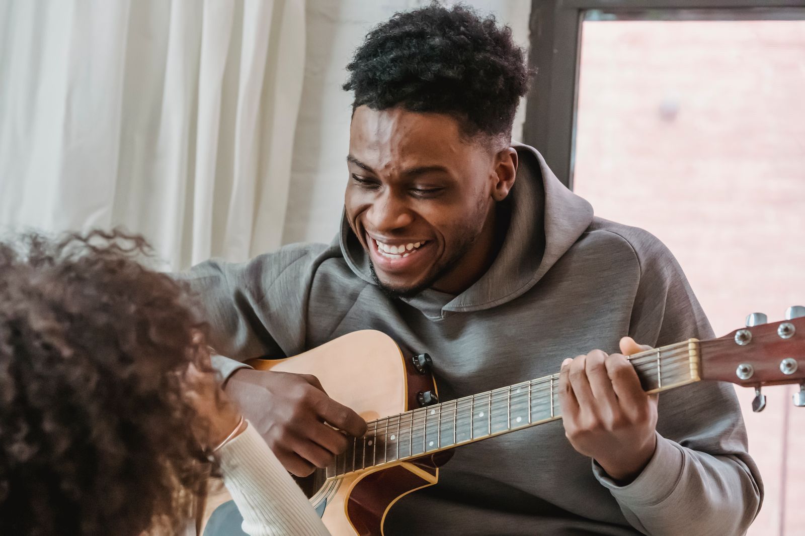 A person happily playing guitar, absorbed in something they genuinely enjoy