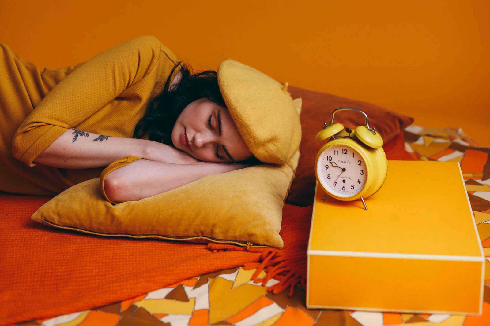 A person asleep beside an alarm clock, sleeping past the planned wake-up time
