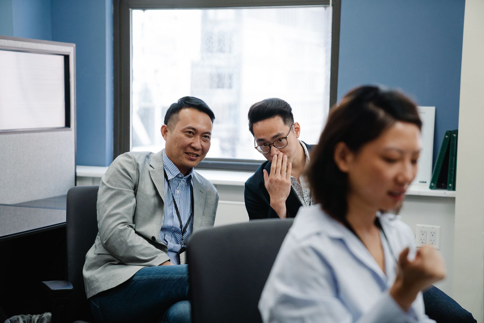 One colleague leaning in to whisper to another in an office