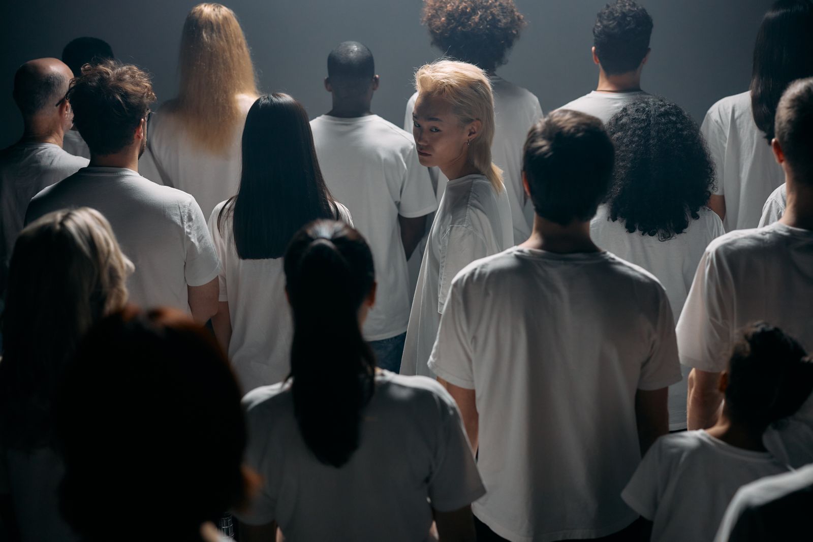 A crowd all facing one way with one person turning a different direction