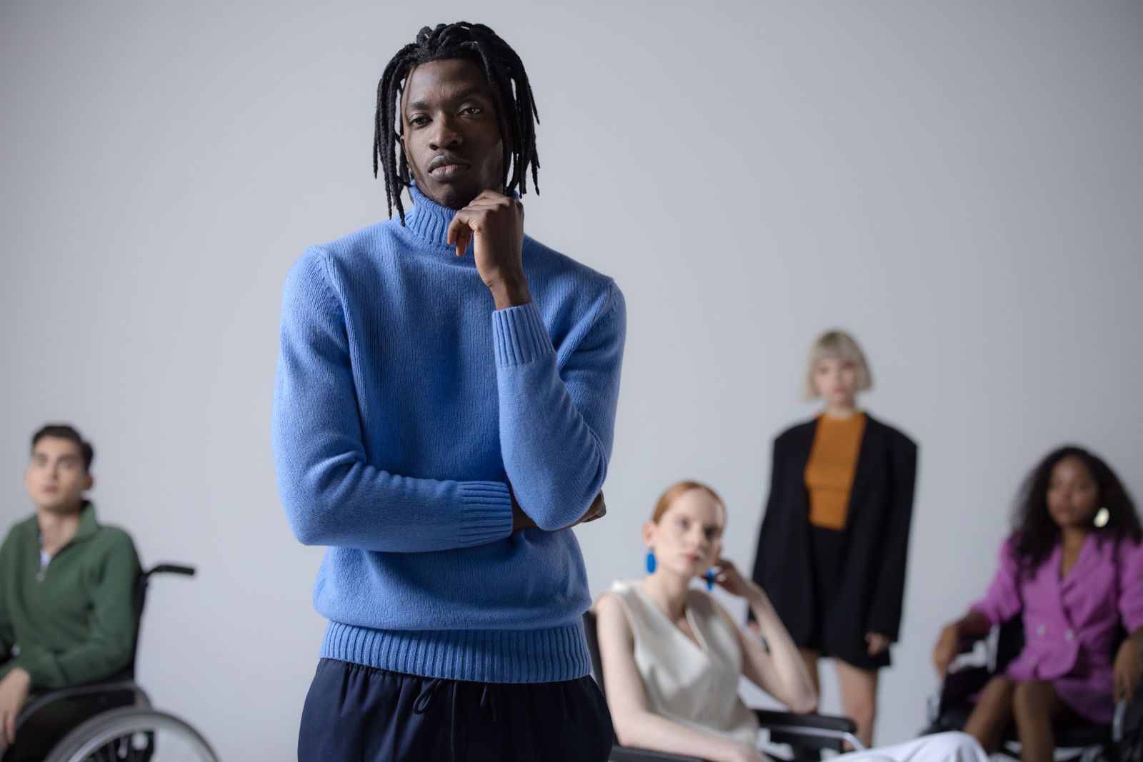 A person standing thoughtfully apart while a group sits behind him
