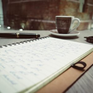 Minimal writing desk workspace with notebook, pen, and coffee cup for creative planning and idea generation
