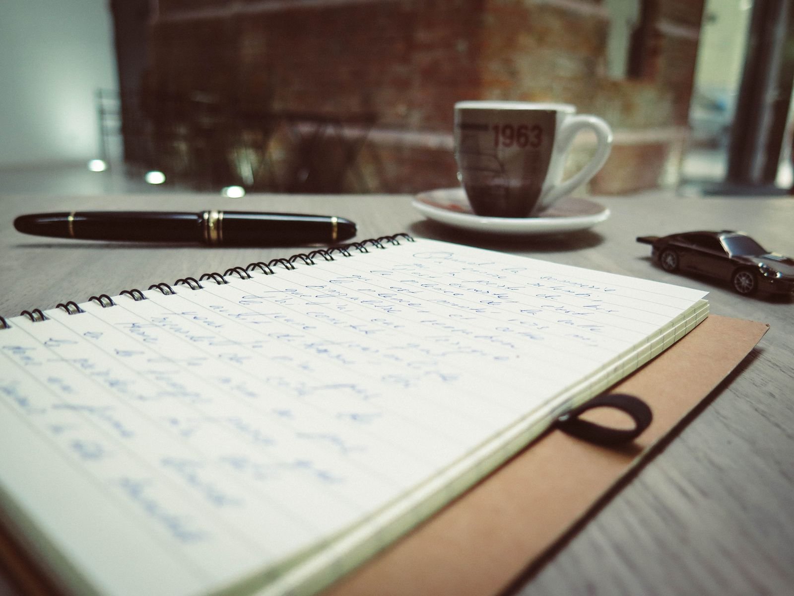 Minimal writing desk workspace with notebook, pen, and coffee cup for creative planning and idea generation