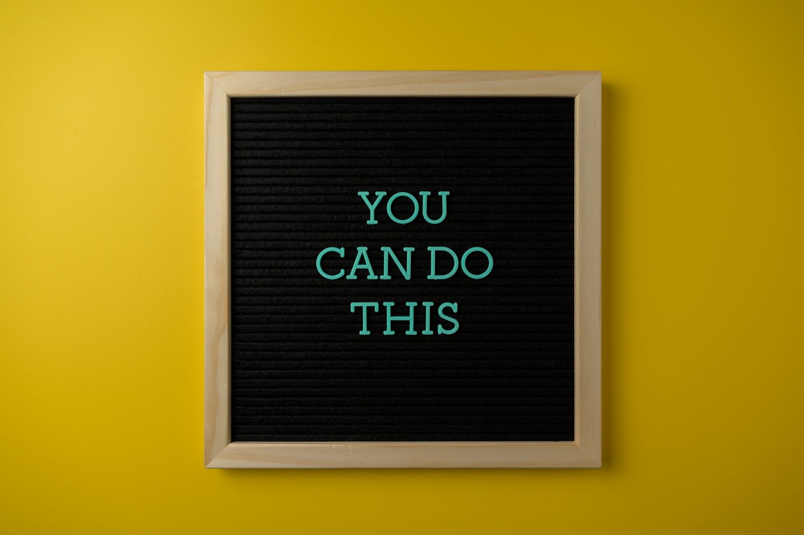 A framed felt letter board reading You Can Do This against a bright yellow background, representing motivation, drive, and encouragement.