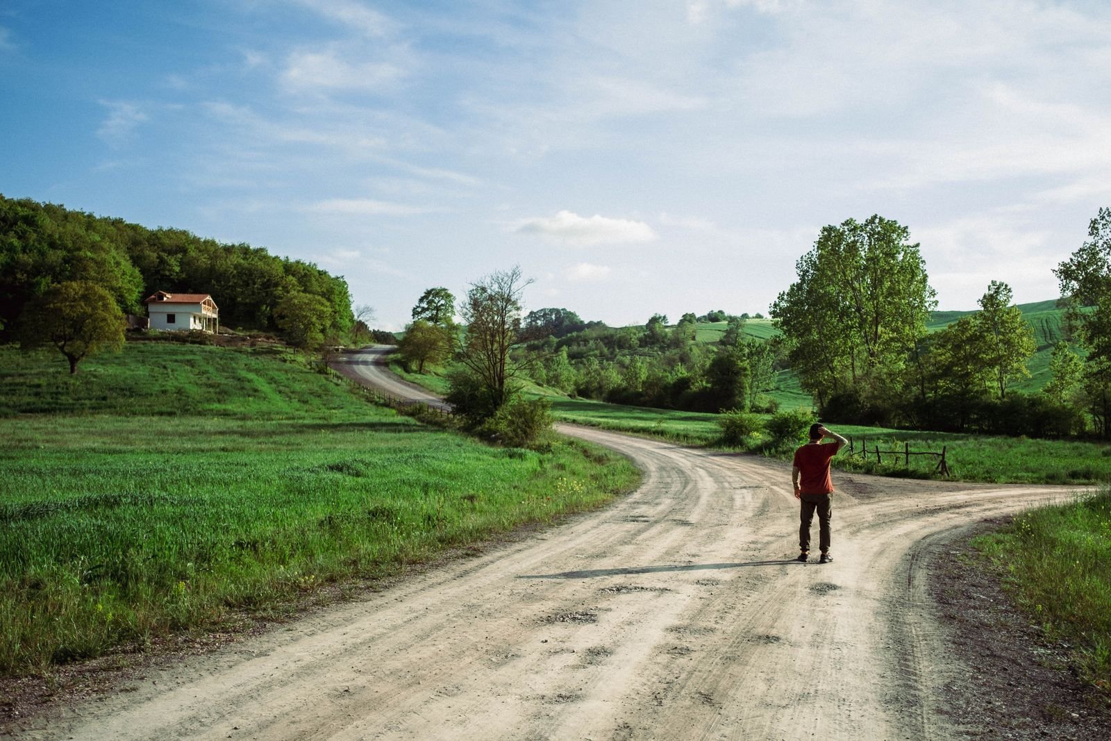 A person standing where a country road splits into two directions