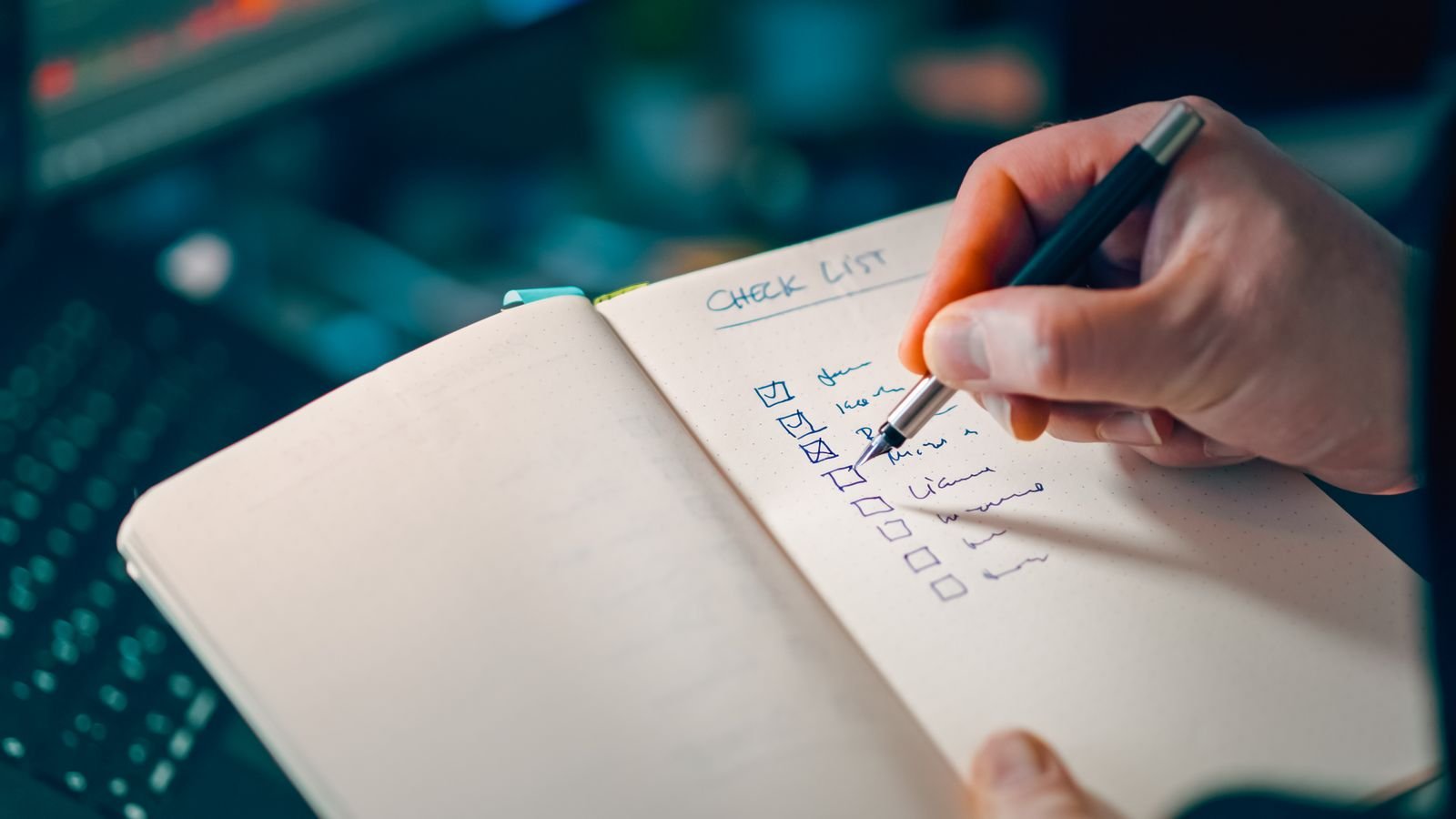 A hand writing a short checklist in a notebook