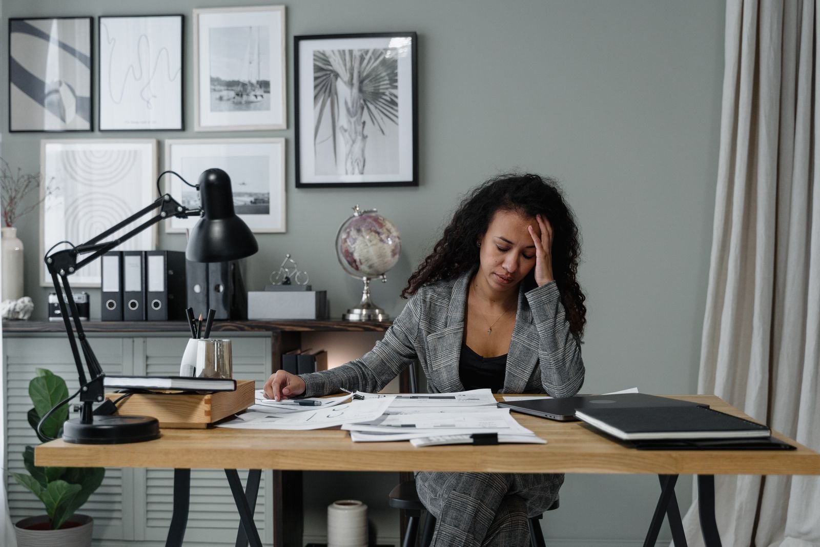 A person sitting at a desk with papers, hand to their head, looking mentally tired