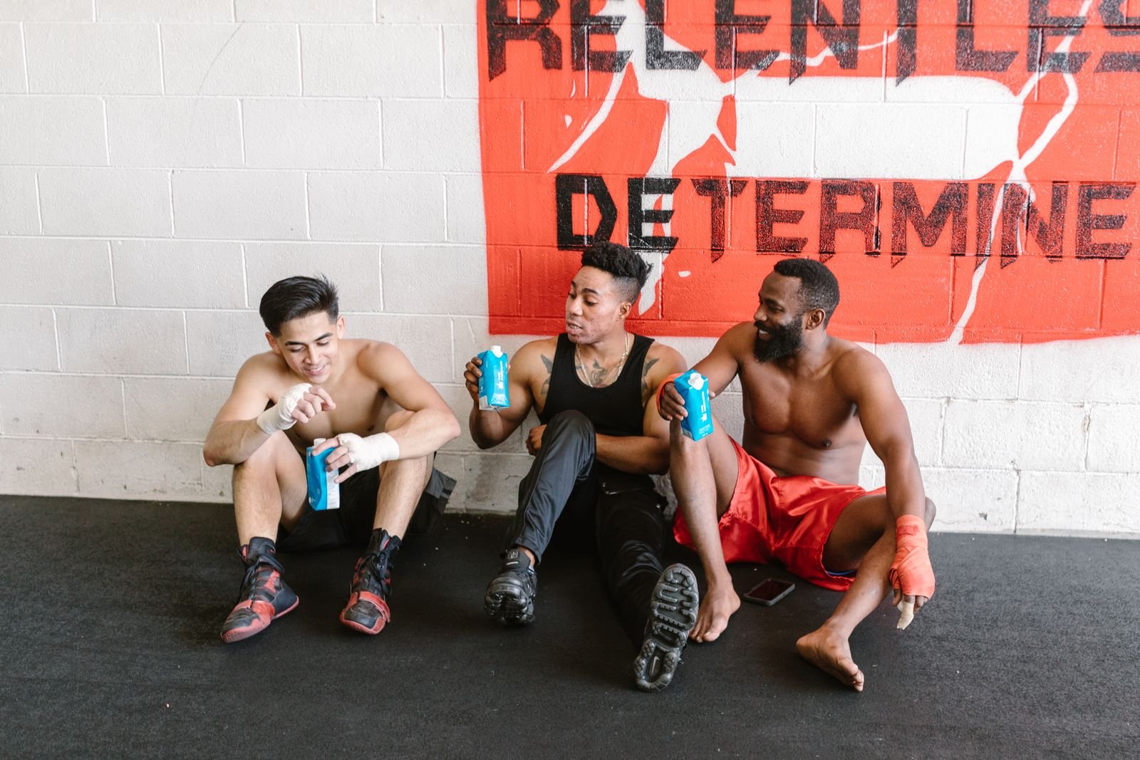 Three friends sitting together resting and talking at the gym