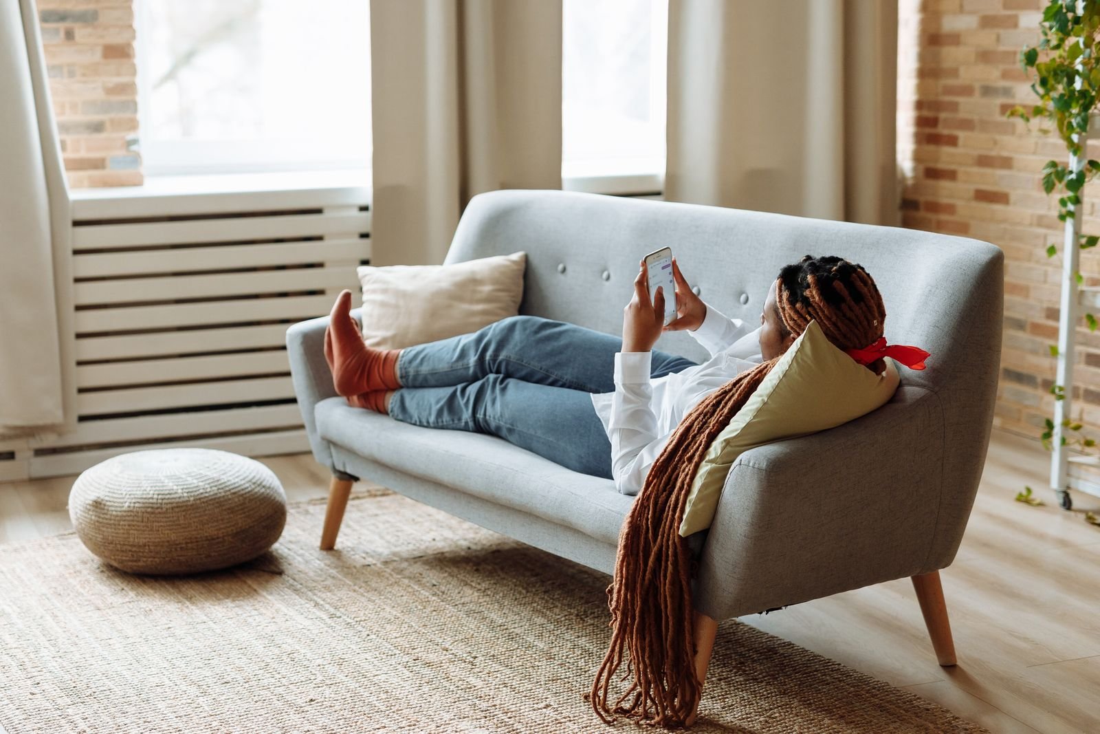 A person lying on a couch looking at their phone during the day