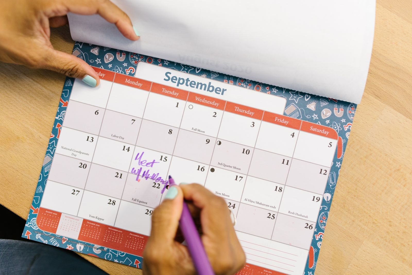 A hand writing on a monthly wall calendar