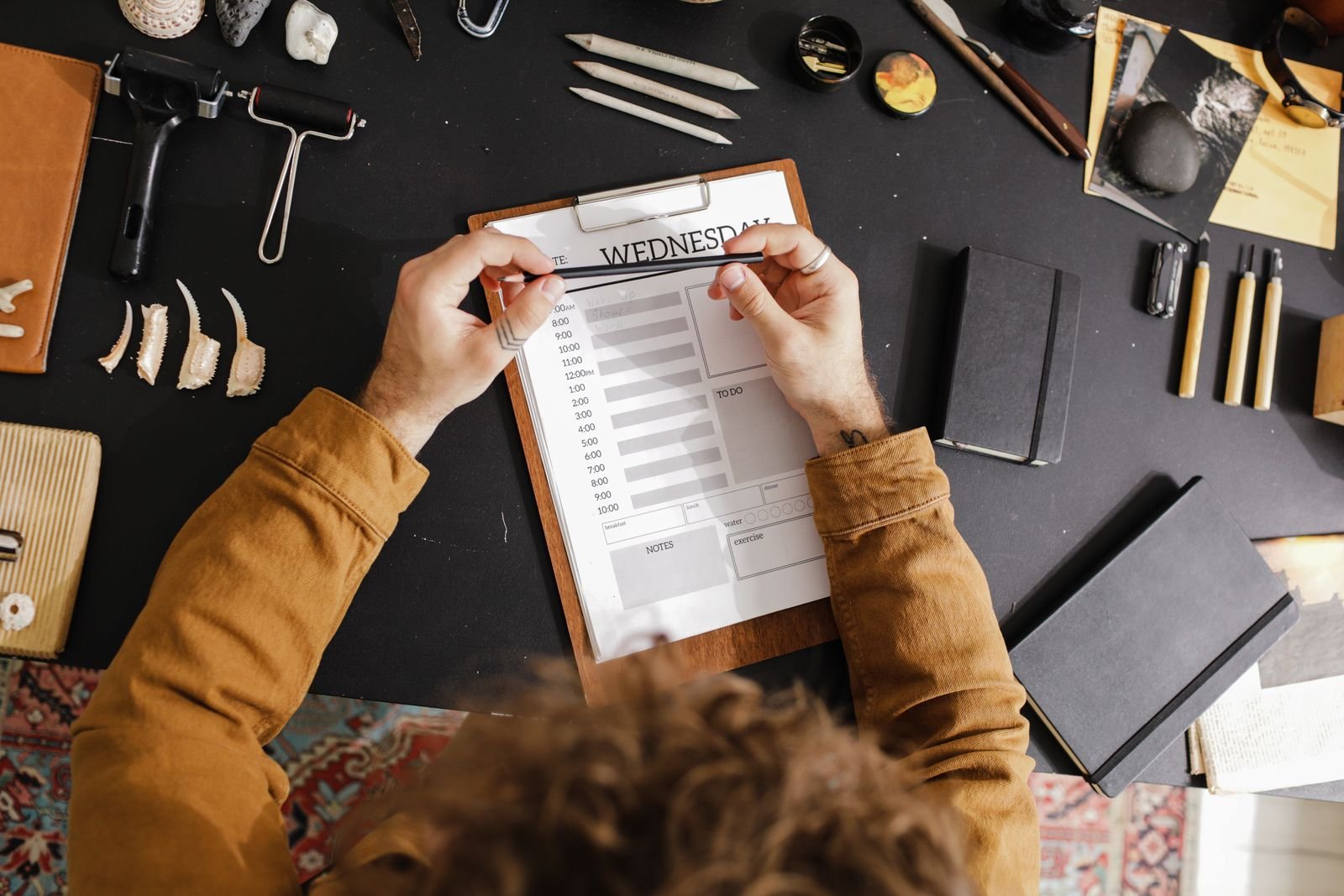 A person filling in a blank weekly planner at a tidy desk
